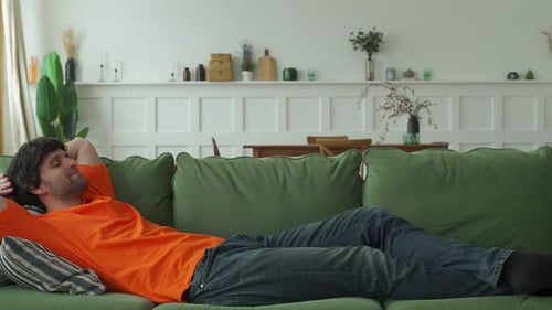 Man Lying on a Green Sofa in a Home