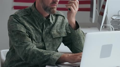 Man in Camouflage Using Radio and Laptop