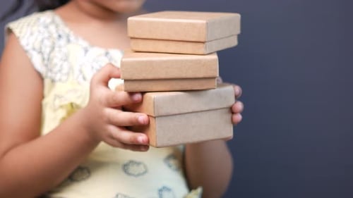 Girl Holding Stack of Cardboard Gift Boxes