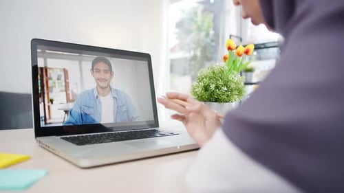 Asian muslim businesswoman using laptop talk to colleague about plan by video call online meeting.