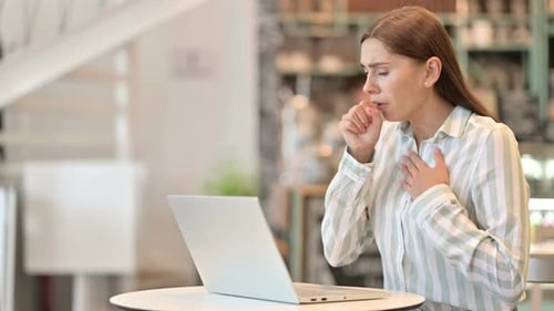 Sick Young Latin Woman with Laptop Coughing in Cafe