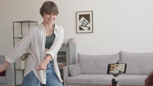Joven negro grabando a su novia bailando hilo dental en casa