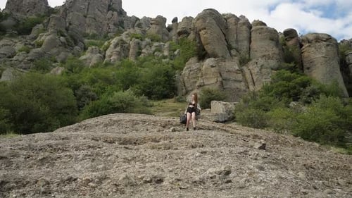 A Girl in Short Shorts and a Light Cape Goes Down the Mountainside
