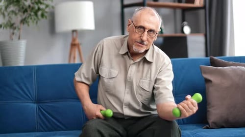 Senior Man Lifts Dumbbells on Couch at Home
