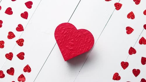 Vlentine's Day Composition. Heart Shaped Sequins Placed on White Wooden Table