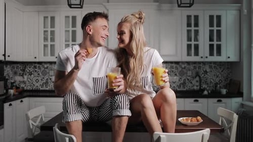 Happy Couple Sharing Food, Kissing in Kitchen at Breakfast
