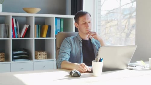 Young male entrepreneur works at home office at the computer.