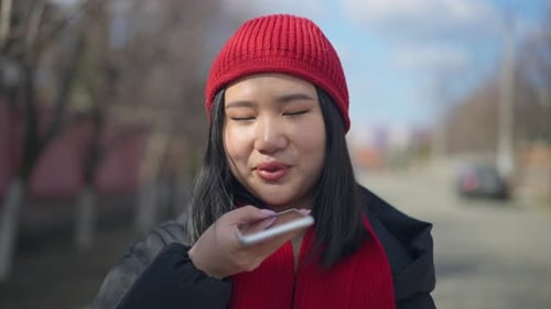 Young Woman Uses Voice Assistant on Phone Outdoors