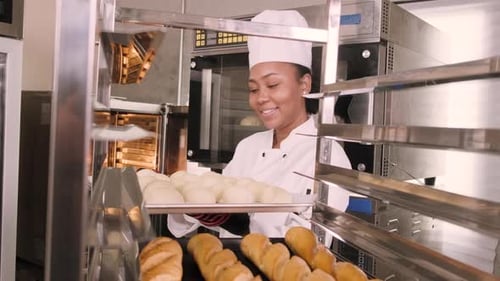 Smiling Baker Arranges Dough in Commercial Kitchen