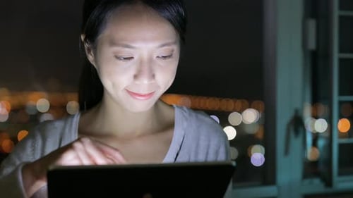 Woman Using Tablet at Night in City Apartment