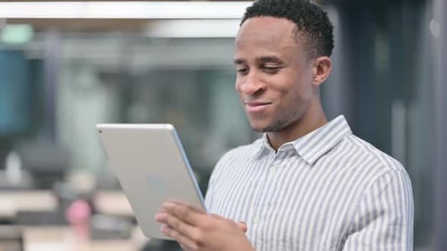 Man Smiling While Using Tablet in Office