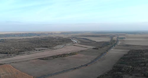 Panoramic View Of A Countryside With Road And Railway Near River Stream During Daytime. Aerial