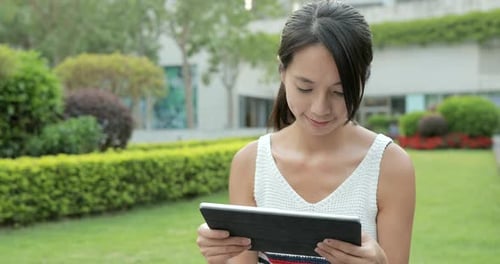 Woman using digital tablet at outdoor park