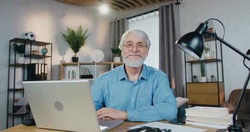 Senior Man Smiling at Laptop in Home Office