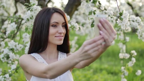 Beautiful Woman Taking Selfie in Spring Blossom Orchard