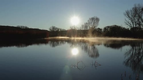 Fog Slowly Rolls Across a Lake at Sunrise
