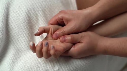 Closeup View of a Male Physiotherapist Doing Finger and Palm Massage to Young Woman at Spa Salon