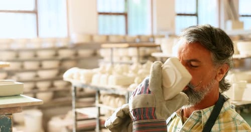 Potter Inspects Ceramic Bowl in Bright Workshop