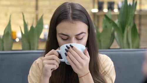 Smiling Woman Drinking Coffee in an Urban Cafe