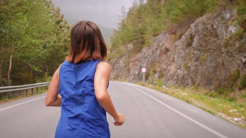 Woman Runs on Road in Mountains