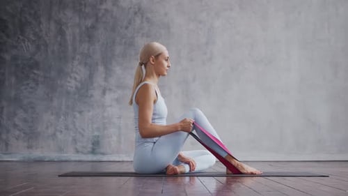 Woman Exercising With Resistance Band Sitting on Mat