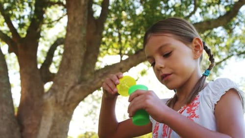 Girl blowing iridescent bubbles in the park