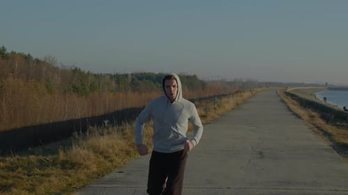 Man Jogging On Rural Path Near Body of Water