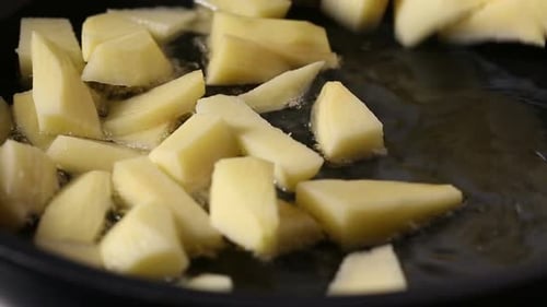 Putting Fresh Raw chopped Potatoes In Pan With Hot sunflower Oil