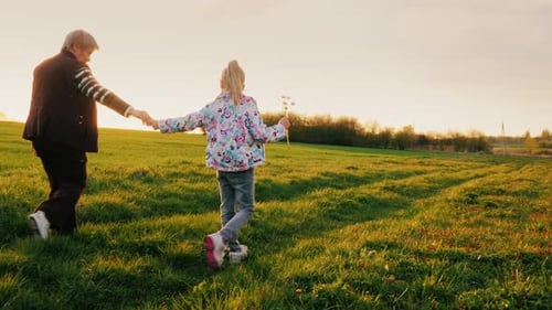 Senior Adult and Child Walking in Golden Field