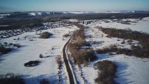 Aerial View of an Asphalt Road Surrounded By Snow in the Countryside