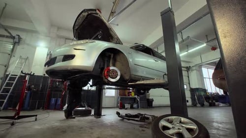 The car goes down on the lift in the auto repair shop