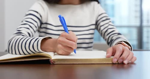 Person Writing in a Notebook at Desk