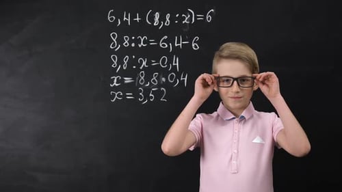 Child Standing Next to Math on Chalkboard