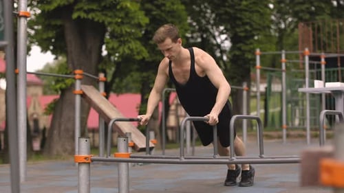 Handsome Caucasian Sports Man Doing Push Up Exercise on Parallel Bars at Outdoor Gym