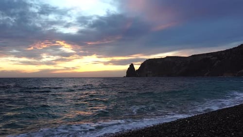 A Red Burning Sunset Over the Sea with Rocky Volcanic Cliff