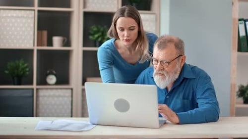 Senior Man Learns Computer Skills with Young Adult Female