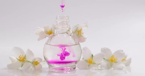 Pink Dye Dropped Into Glass Bottle with Flowers