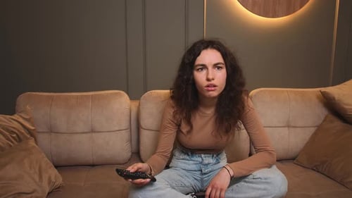 Woman Holding Tv Remote Control Changing Channel Searching Show Sitting Cozy Couch Casual Outfit