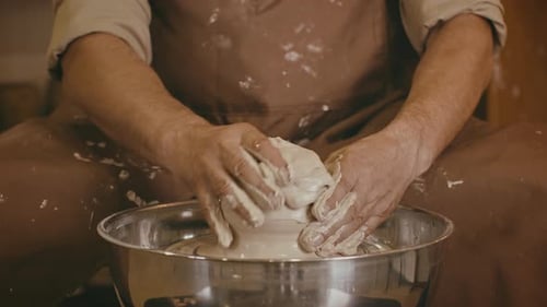 Un homme méconnaissable échoue à fabriquer une tasse en argile sur un tour de poterie à l'intérieur