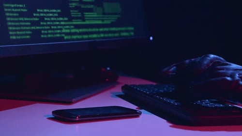 Spy Types the Virus Data, on the Table There Is a Phone. Close Up