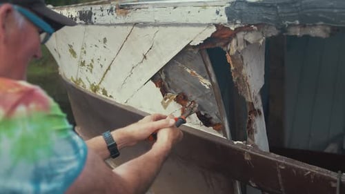 Man Repairing Old Wooden Boat with Hand Tools