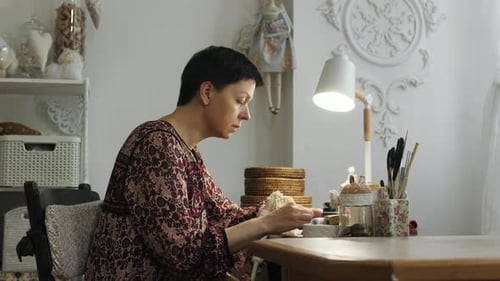 Woman drawing the eyes of a doll