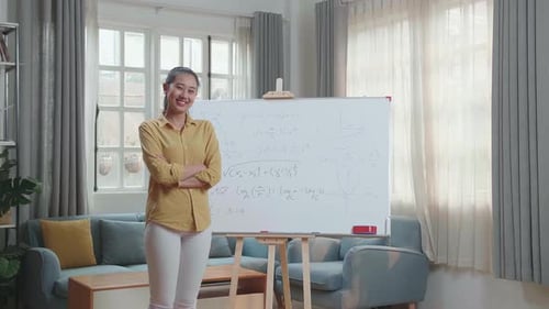 Asian Female Teacher Crossing Arms And Smiling To Camera While Teaching Math At Home