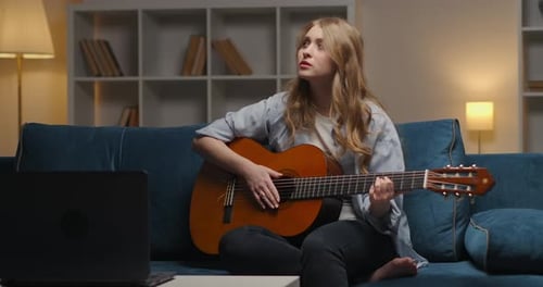 Divertissement à domicile en soirée pendant l'auto-isolement et le verrouillage Une femme joue de la musique sur un support de guitare