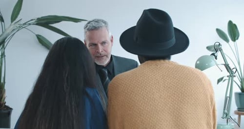 Mature realtor and couple discuss details of contract over shoulder view