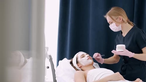 Cosmetóloga unta la cara de una niña con crema en un salón de belleza
