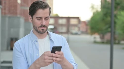 Young Adult Using Smartphone on City Street