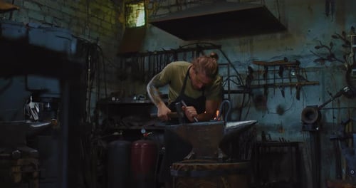 Blacksmith Hammering Glowing Metal on Anvil in Workshop