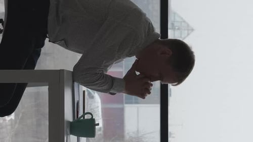 Man with Head in Hands Near Office Window