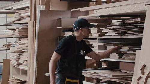Man in a Carpentry Workshop Takes a Wooden Detail From the Shelf
